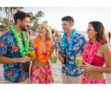 Four people on a beach wearing colorful leis and floral outfits, enjoying drinks.
