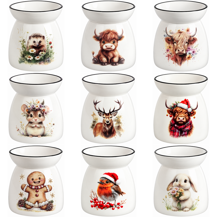 Nine white ceramic scented oil burners arranged in a 3x3 grid, each decorated with a different cute animal illustration including a hedgehog, cow, buffalo, chameleon, deer, snowy buffalo, gingerbread man, robin, and rabbit.