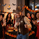 Man in cowboy costume with toy guns at a Halloween party with friends.