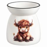 A white ceramic oil burner or scented candle holder with a black rim around the top bowl, featuring a detailed illustration of a cute brown highland cow on the front.