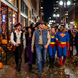 People in costumes walking down a city street at night.