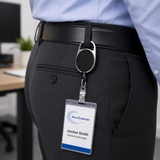 A close-up of a person wearing black dress pants and a light blue dress shirt, with a black belt and a retractable badge reel clipped to the back pocket. The badge reel holds a clear ID badge with the name Jordan Smith and the AnnZEntertain logo.