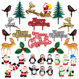 A set of Christmas-themed plastic cake toppers and decorations arranged on a plain white background, including red and gold 'Merry Christmas' signs, green trees, birds, deer, holly, Santa Claus figures, penguins, snowmen, and other holiday motifs.
