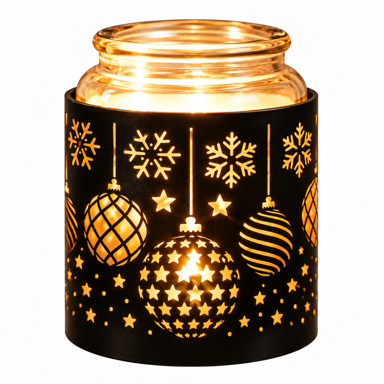 A lit glass jar candle holder with a black holiday-themed sleeve featuring laser-cut snowflakes and ornaments, glowing with warm golden light against a white background.