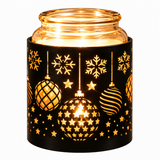 A lit glass jar candle holder with a black holiday-themed sleeve featuring laser-cut snowflakes and ornaments, glowing with warm golden light against a white background.
