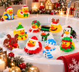 A group of colorful Christmas-themed rubber duckies floating in a bubbling bathtub with running water. The ducks are dressed in holiday outfits including Santa Claus, a snowman, a reindeer, a penguin, and festive hats and scarves.