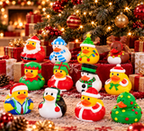 A set of Christmas-themed rubber duck toys arranged in front of a decorated Christmas tree with wrapped gifts. The collection includes ducks dressed as Santa Claus, a snowman, an elf, a Christmas tree, a penguin, a reindeer, and a snowman with a Santa hat.