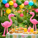 Tropical-themed party with inflatable flamingos, colorful balloons, and a table set with drinks and snacks.