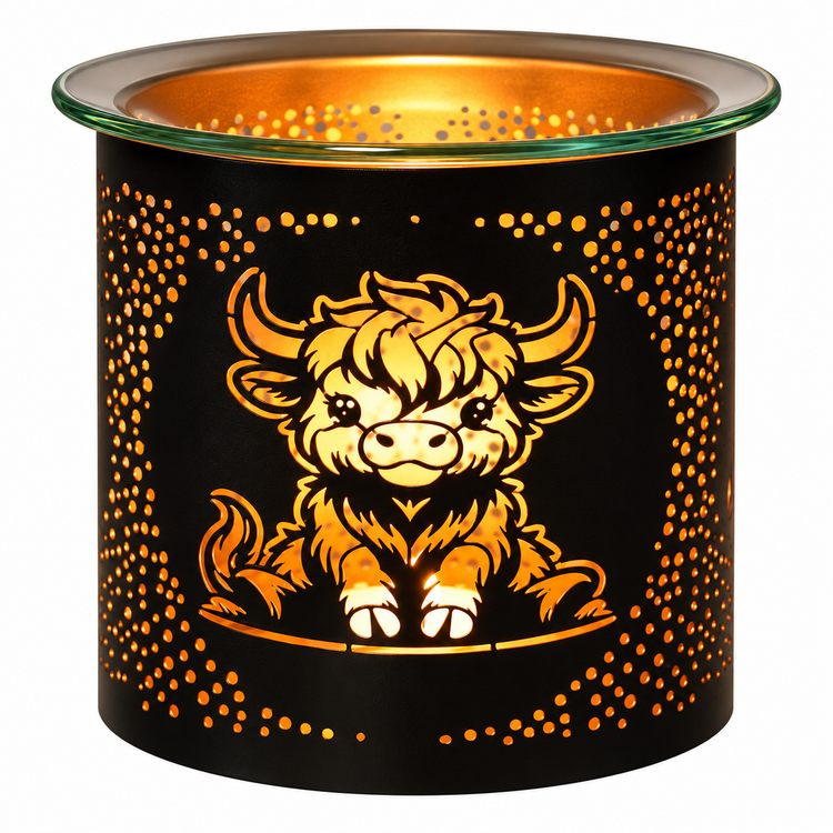 A black metal candle holder with a glowing warm interior, featuring a cartoon Highland cow illustration and a border of small cutout dots on the front, with a clear glass rim at the top.