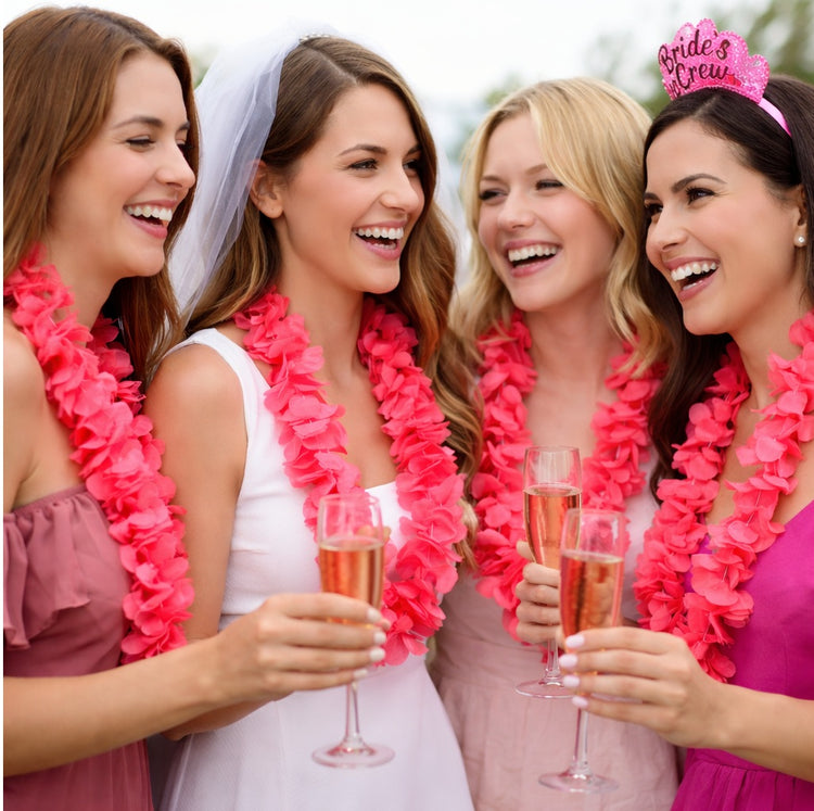 Four women celebrating with pink leis and drinks, one wearing a 'Bride to Be' tiara.