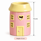 Pink ceramic house-shaped holder with a yellow roof, yellow windows, and a yellow door, shown on a white background with height measurement annotations reading 12 cm.