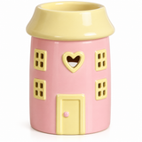 A pink ceramic candle holder shaped like a house, featuring a yellow roof, yellow window frames, a yellow heart-shaped window in the center, and a yellow door with a small pink knob.