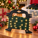 A spool of Christmas string lights with green wire and warm yellow glowing bulbs, displayed on a wooden table with a blurred festive background featuring a decorated Christmas tree, ornaments, and wrapped gifts.