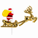 A Christmas-themed plastic cake topper featuring Santa Claus in a red and white suit pushing a sleigh with a golden reindeer and yellow sack, mounted on a white stick.