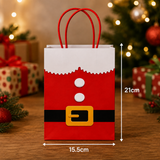 A Christmas-themed paper gift bag designed to look like Santa's suit, with red handles, a red body, white faux fur trim, white buttons, and a black belt with a gold buckle. White dimension lines on the right and bottom indicate a height of 21cm and a width of 15.
