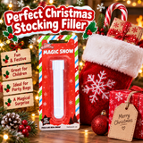 A festive Christmas stocking filler product displayed with holiday decorations. The main item is a packaged 'Magic Snow' toy shown in its red blister card packaging, alongside a red Christmas stocking, wrapped presents, pine branches, ornaments, and a 'Merry Christmas' tag.
