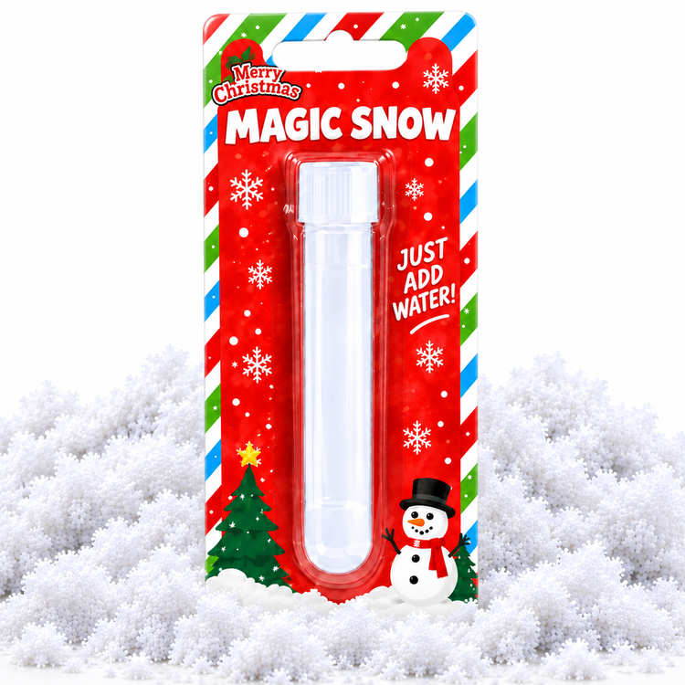 A plastic magic snow tube in its festive red holiday blister packaging, displayed on a bed of white faux snow. The packaging features 'Merry Christmas MAGIC SNOW' text, candy cane stripes, a snowman illustration, and instructions to 'JUST ADD WATER!'.