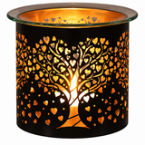 A black metal candle holder with a laser-cut tree of hearts design, illuminated from within to cast a warm golden glow, shown on a plain white background.