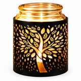 A black metal candle holder with a laser-cut tree of life design, illuminated from within by a warm glowing light, set against a plain white background.