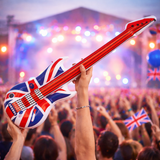 Inflatable guitar with British flag design held by a person at a concert with a crowd and stage lights in the background.
