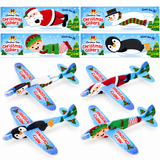 Six Christmas-themed foam airplanes arranged in two rows on a white background, each with different holiday character graphics including Santa, a snowman, an elf, and a penguin. The planes are light blue with red text reading 'SPRINGTIME CLINIC' and colorful festive illustrations.