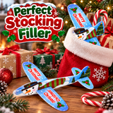 A festive Christmas-themed product display featuring a blue wooden airplane toy labeled 'Merry Christmas!' and 'Perfect Stocking Filler,' shown alongside a red Santa sack, wrapped gifts, candy canes, pinecones, and holiday lights. The text 'Perfect Stocking Filler' appears prominently in the upper left.