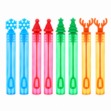 Six colorful bubble wand tubes with festive tops arranged in a row on a white background. The designs include a blue snowflake, a red Santa hat, a pink Santa hat, a green Christmas tree, a green Christmas tree, and an orange reindeer antler.