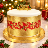 A round Christmas cake with white frosting on top and a textured gold body decorated with a red holly pattern, sitting on a gold cake stand. A gold 'Merry Christmas' topper is placed on top.