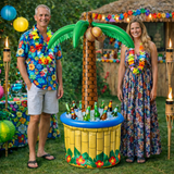 Two people standing next to a tropical-themed inflatable cooler with drinks on a grassy area.